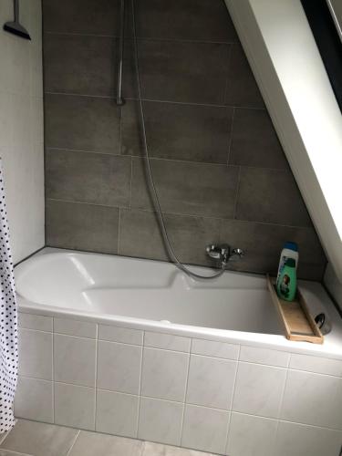 een badkamer met een bad en een douche bij Holiday Home de witte raaf with garden and hottub in Noordwijk aan Zee