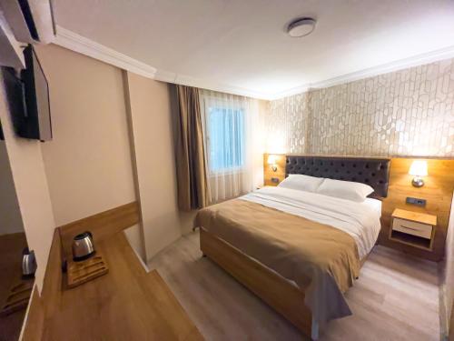ein Hotelzimmer mit einem Bett und einem Fernseher in der Unterkunft Helen Inn in Izmir