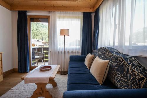 a living room with a blue couch and a table at Hotel Tyrol in Selva di Val Gardena