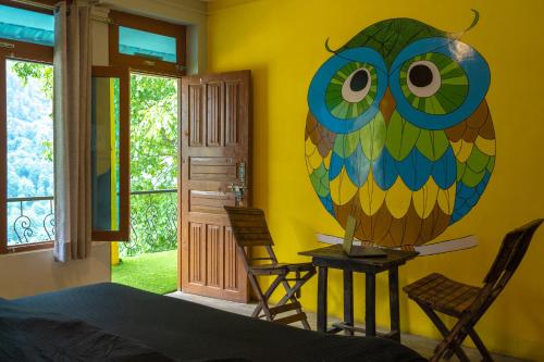 a bedroom with a large colorful owl painted on the wall at Whoopers Hostel Tosh in Tosh
