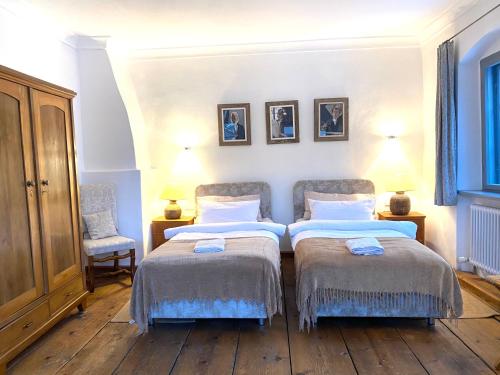 a bedroom with two beds and two chairs at Benefizium Denklingen - Anno 1713 in Denklingen