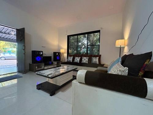 a living room with a couch and a table at Stay Leisurely Organic Brew Pool 2BHK, Karjat in Karjat