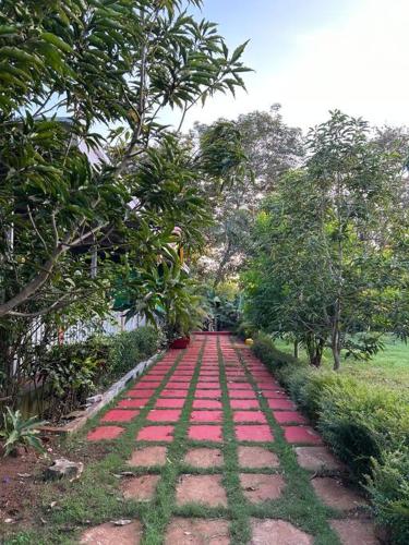 a walkway with red stones and trees in a park at Stay Leisurely Organic Brew Pool 2BHK, Karjat in Karjat