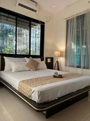 a large bed in a bedroom with windows at Stay Leisurely Organic Brew Pool 2BHK, Karjat in Karjat