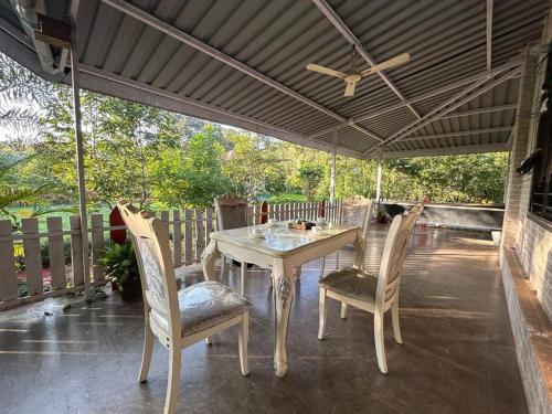 a table and chairs on a patio with an umbrella at Stay Leisurely Organic Brew Pool 2BHK, Karjat in Karjat