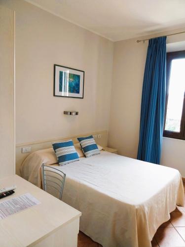 a bedroom with two beds with blue curtains at Hotel Moderno in SantʼAntìoco