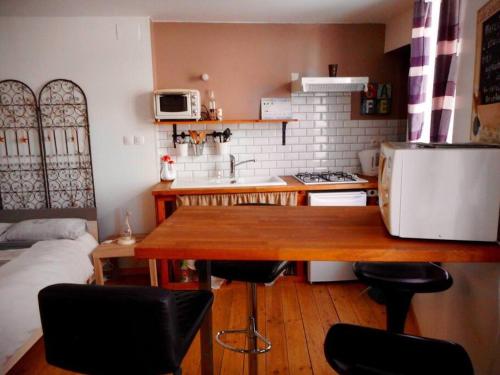 une cuisine avec une table en bois et quelques chaises dans l'établissement Studio cosy au cœur de la nature, à Gorze
