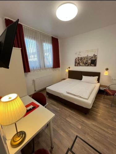 a bedroom with a bed and a desk with a lamp at Hotel Columbus und Glamping in Bremerhaven