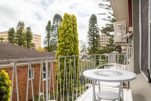 a balcony with a white table and a tree at Lotus Stay Manly - Apartment 29A in Sydney