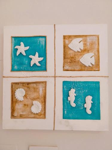 four pieces of art on a wall with seashells at Hotel Moderno in SantʼAntìoco