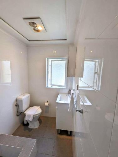 a white bathroom with a toilet and a sink at Lotus Stay Manly - Apartment 31H in Sydney