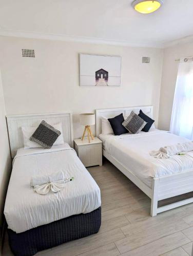 two beds in a bedroom with white walls at Lotus Stay Manly - Apartment 31H in Sydney