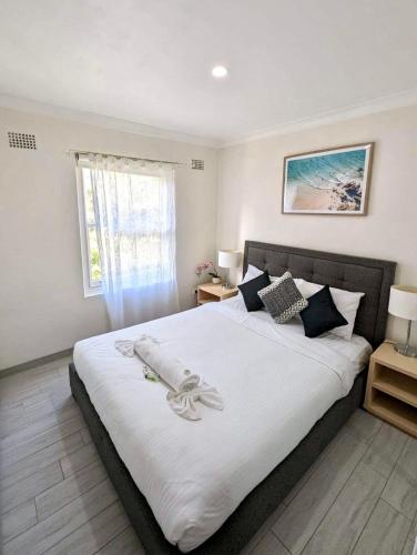 a bedroom with a large bed with white sheets and a window at Lotus Stay Manly - Apartment 31H in Sydney