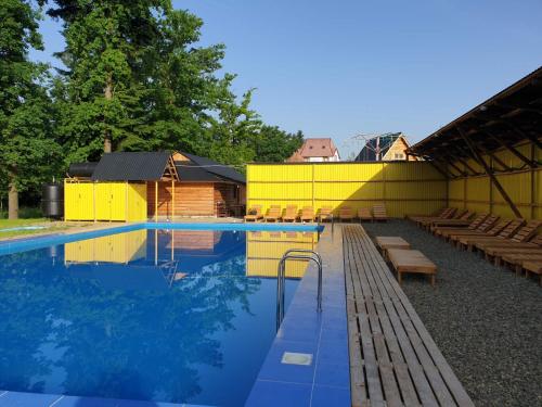 a swimming pool with benches and a yellow building at Ворота Карпат in Dilyatyn