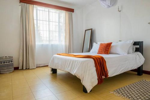 a bedroom with a bed with an orange blanket on it at The Hillpoint Nest in Nairobi