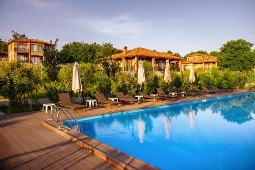 a hotel swimming pool with chairs and umbrellas at Schuchmann Wines Château,Villas & SPA in Tʼelavi