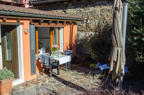 un patio con sombrilla, mesa, sillas y sombrilla en Rustico al Sole - Just renewed 1bedroom home in Ronco sopra Ascona en Ronco sopra Ascona