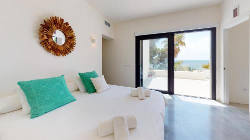 a white bedroom with a large bed with a large window at Villa Higueras in Santa Eularia des Riu