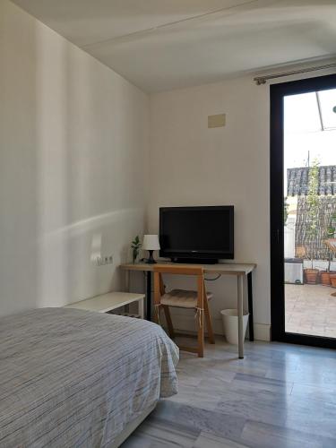 - une chambre avec un lit et un bureau avec une télévision dans l'établissement White Room Alameda, à Séville