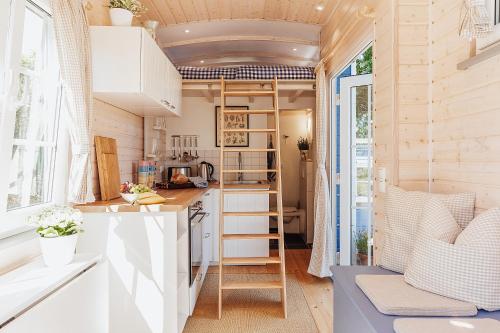uma pequena cozinha com armários brancos e uma escada em Tinyhouse am Obsthain em Poseritz