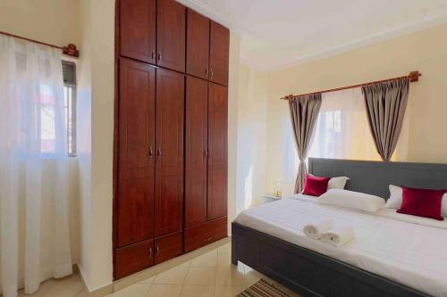 a bedroom with a large bed with red pillows at Cozy Apartment within Acacia mall area limits, Unlimited WIFI, Netflix, Free Parking in Kampala