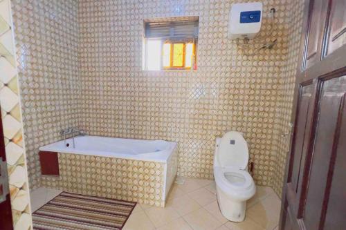 a bathroom with a toilet and a tub and a sink at Cozy Apartment within Acacia mall area limits, Unlimited WIFI, Netflix, Free Parking in Kampala