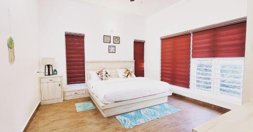 a bedroom with a bed and a window with red blinds at ROBUSTA FOREST Home stay in Sultan Bathery