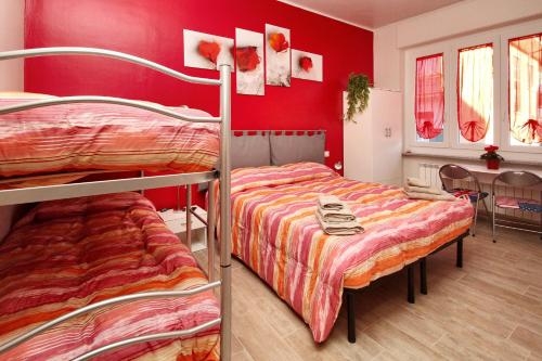 クーネオにあるB&B Il Rosso e il Bluの赤い壁のドミトリールームの二段ベッド2台