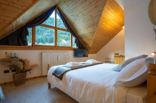 a bedroom with a large bed and a large window at Fior di Roccia - Valmalenco - Hotel & Mountain Restaurant in Lanzada