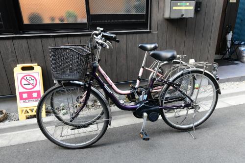 ein Fahrrad mit einem Korb neben einem Gebäude in der Unterkunft 無料wi-fi JING HOUSE 秋葉原 電動自転車レンタル in Tokio
