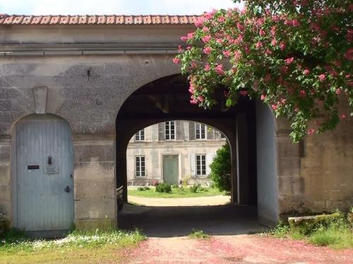 an archway with a building with a blue door at Le Dojo du Plessis in Mareuil