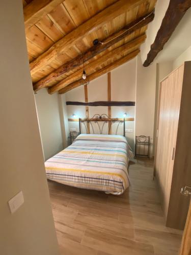 una camera con letto in una stanza con soffitti in legno di Casa Juan a Gea de Albarracín