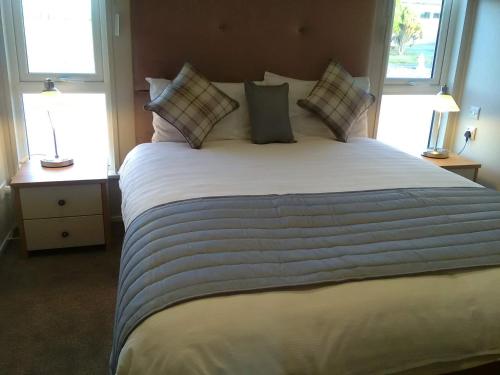 uma cama grande num quarto com 2 janelas em Turnberry lodge em Girvan