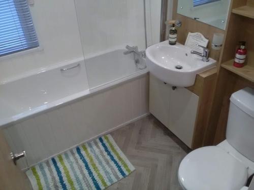 uma casa de banho com um lavatório, um WC e uma banheira em Turnberry lodge em Girvan