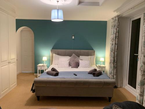 a bedroom with a large bed with a blue wall at Ideally located Luxury Country Escape-The Lookout-with private garden dog friendly and private hot tub in Honiton