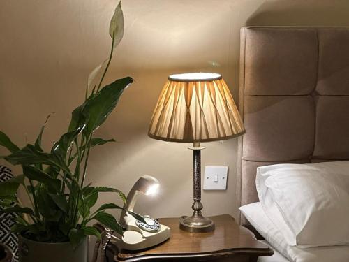 a lamp on a table with a phone and a plant at 1869 - Room Only Boutique Townhouse in Ambleside