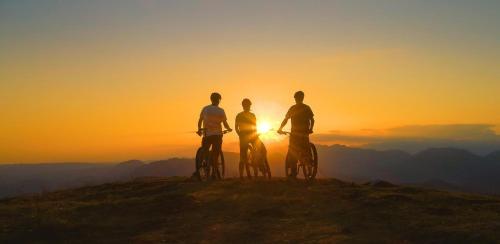 three men standing on a hill with their bikes at sunset at Villa Pieve in Moncalvo