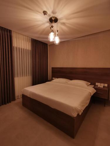 Un dormitorio con una cama grande y una lámpara de araña. en Dara apartment hotel en Umm Uthainah