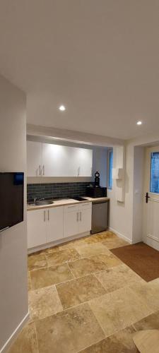 une cuisine avec des armoires blanches et un sol carrelé dans l'établissement APPARTEMENT LES MOUETTES, à Saint-Valery-en-Caux
