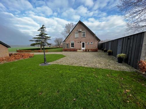 a house with a tree in the middle of a yard at Veldzicht in Klarenbeek