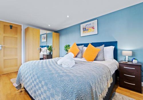 a blue bedroom with a large bed with orange pillows at St Helens Studio with Free Parking by My Getaways in Hove