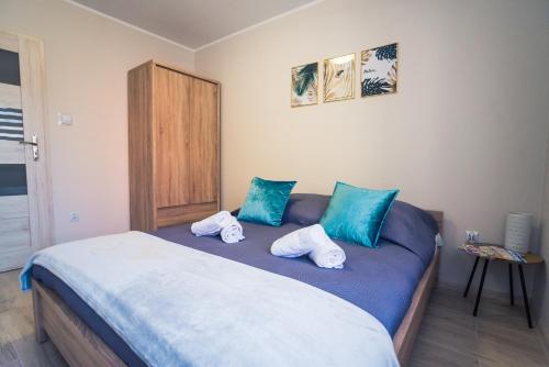 a bedroom with a bed with blue and white pillows at Apartament w Kamienicy na Kłodzkiej in Duszniki Zdrój
