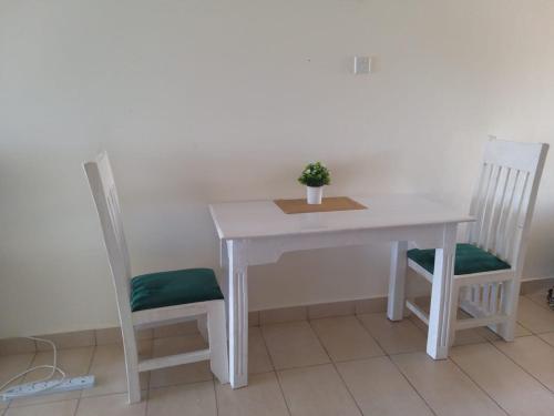 a white table and two chairs with a plant on it at Lux Suites Diani Beachfront Studio Apartments in Ukunda