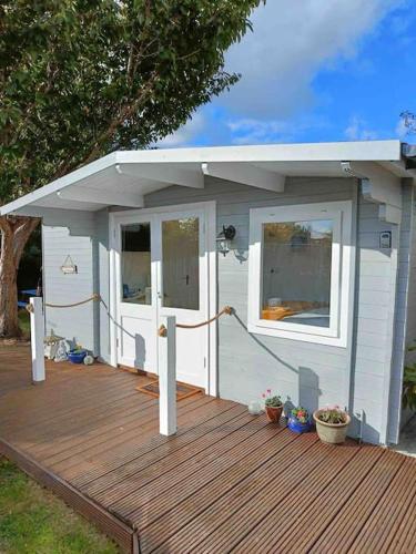a white shed with a roof on a wooden deck at Private Lodge close to beaches and Goodwood in Felpham
