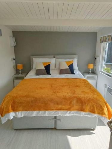 a bedroom with a large bed with orange blanket at Private Lodge close to beaches and Goodwood in Felpham