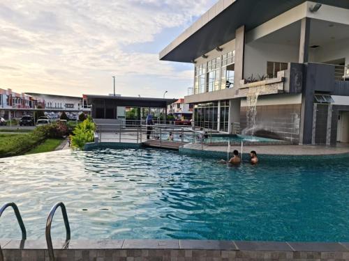 2 personnes dans une piscine en face d'un bâtiment dans l'établissement RHR Deluxe GuestHouse Kinarut Papar Sabah - Pool View, à Papar