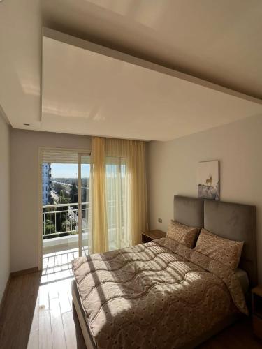 - une chambre avec un grand lit et une grande fenêtre dans l'établissement Shiny appartment in Prestigia, à Rabat