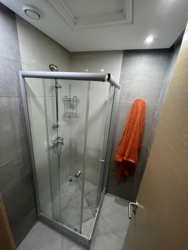 La salle de bains est pourvue d'une cabine de douche et d'une serviette orange. dans l'établissement Shiny appartment in Prestigia, à Rabat