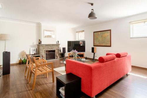 a living room with a red couch and a fireplace at Vinaika Loft in Oeiras