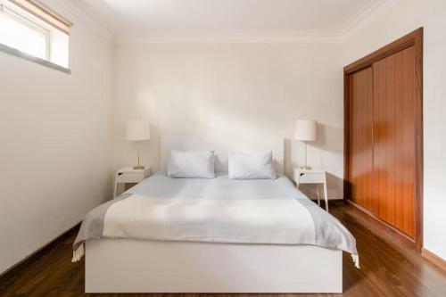 1 dormitorio blanco con 1 cama blanca y 2 mesas en Vinaika Loft, en Oeiras
